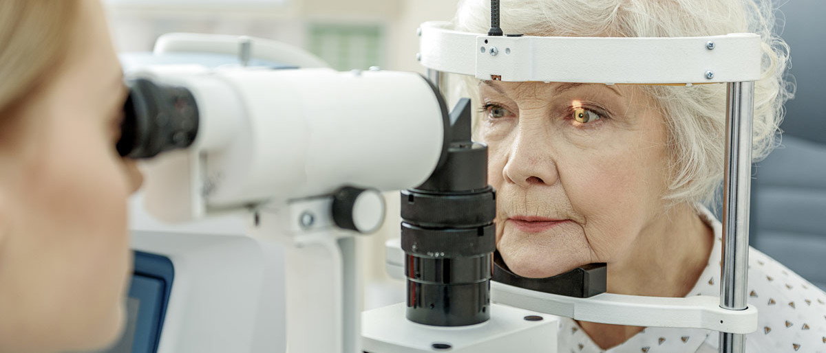 An elderly woman is having her eyes examined by an optometrist for contact lenses.