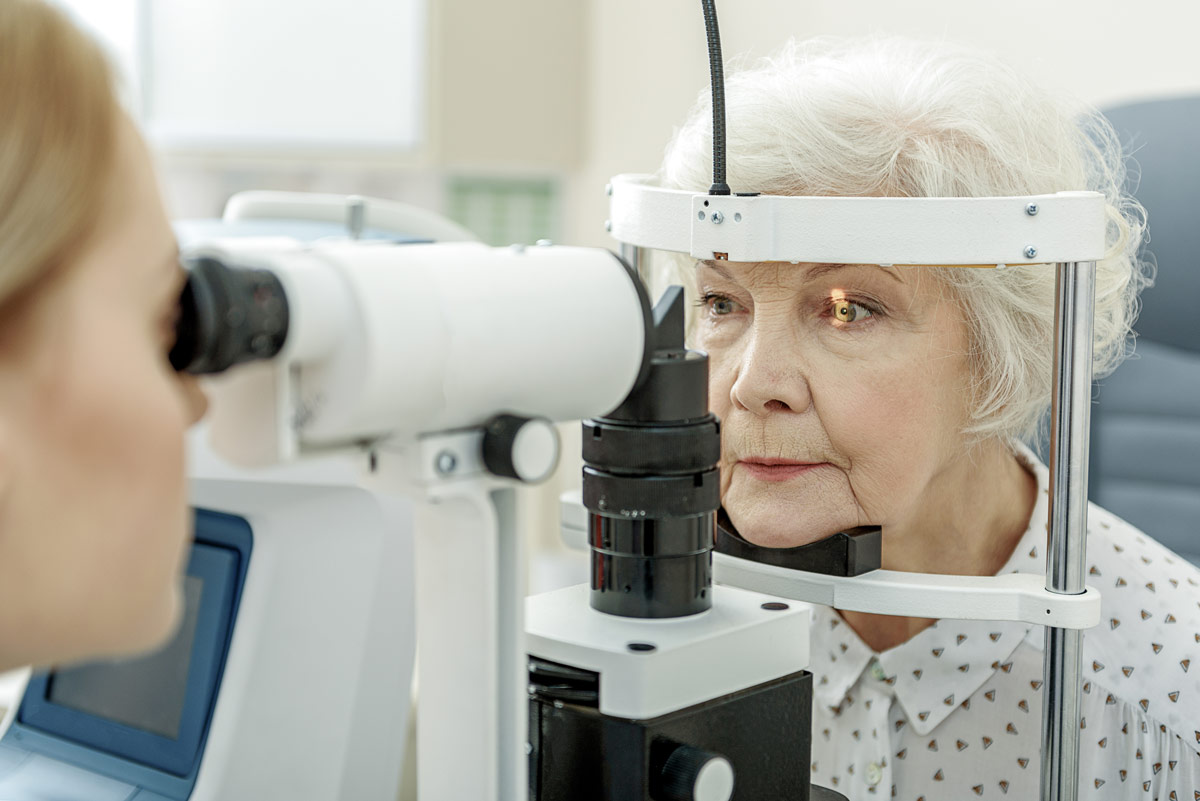 An elderly woman is having her eyes examined by an optometrist for contact lenses.