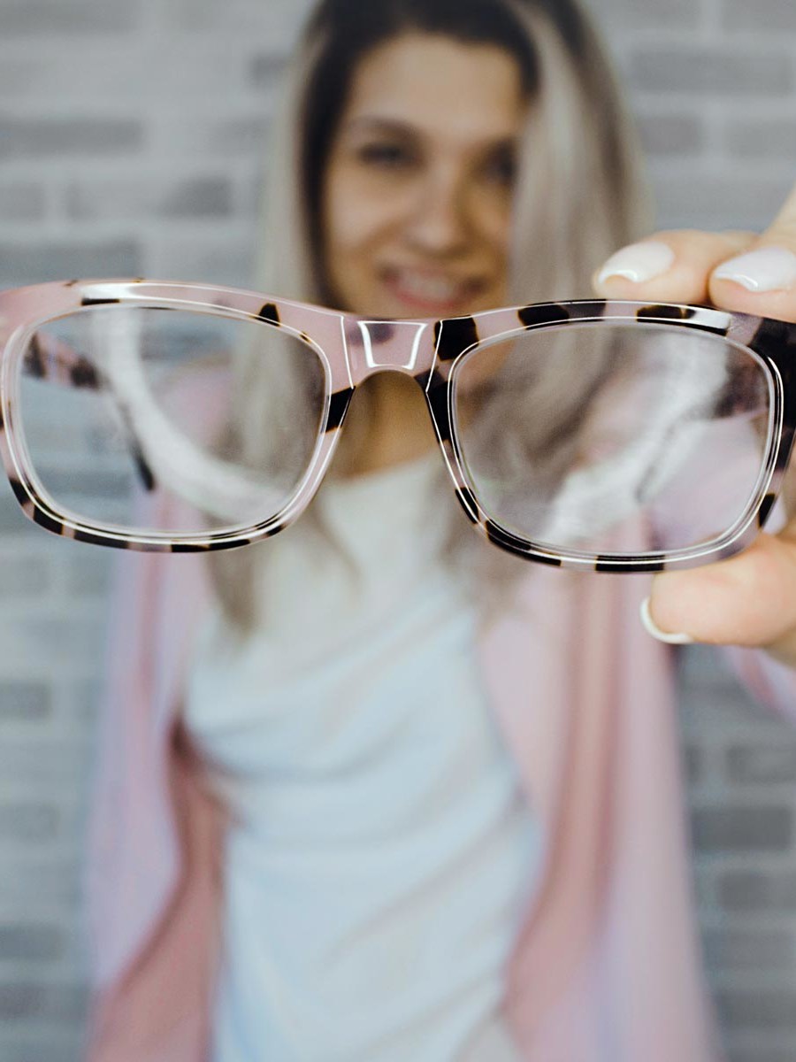 A woman showcasing eyecare with a pair of glasses.
