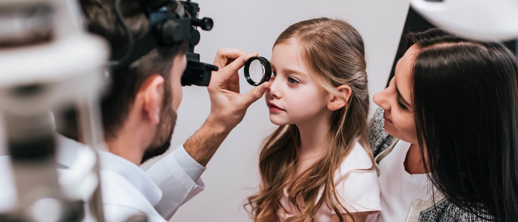 A young girl is receiving eye care from an optometrist.