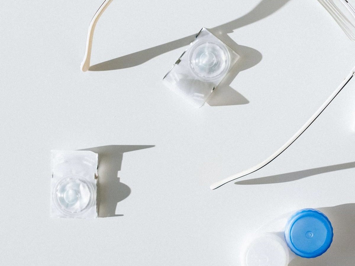 A pair of contact lenses and a pack of condoms on a white surface.