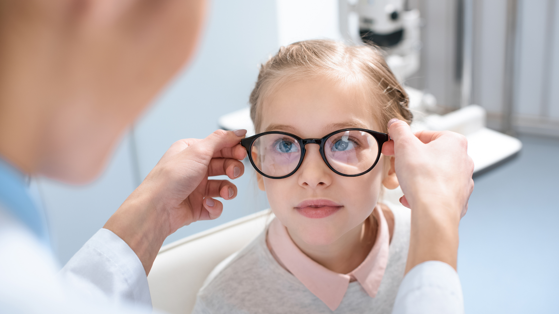 A young girl is getting her glasses checked by an optometrist.