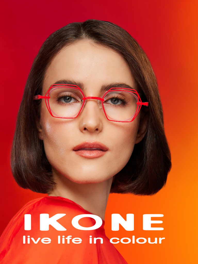 Woman with straight brown hair wearing red glasses and top, against a red-orange background. Text reads, "IKONE live life in colour.